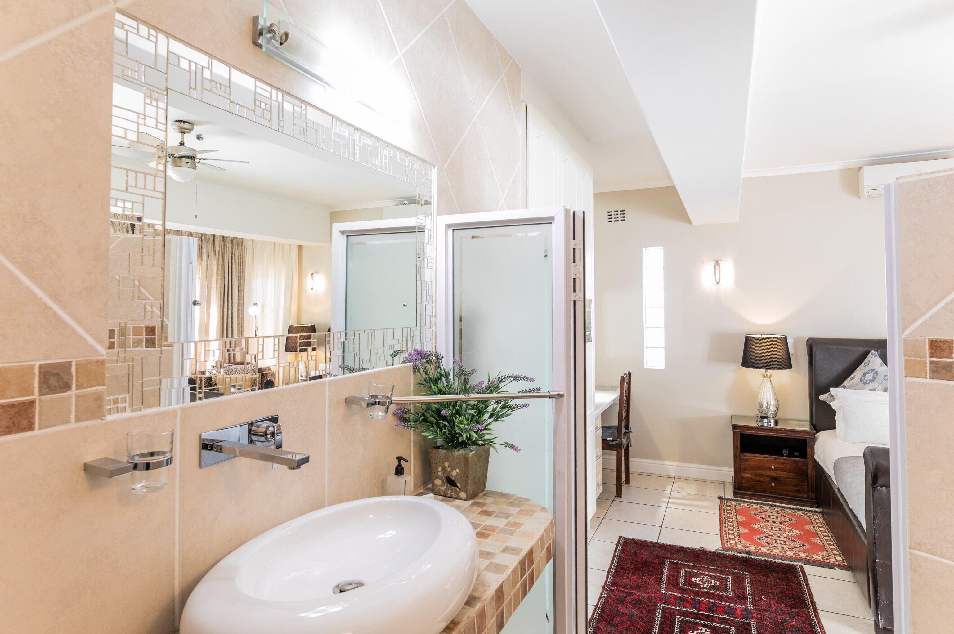A modern bathroom with a large mirror, a sink, and a shower area.