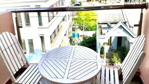 Un balcón con una mesa redonda y dos sillas, con vistas a una zona residencial con edificios y vegetación.