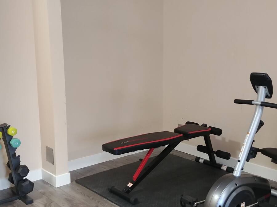 A home gym with a bench, dumbbells, and a stationary bike.