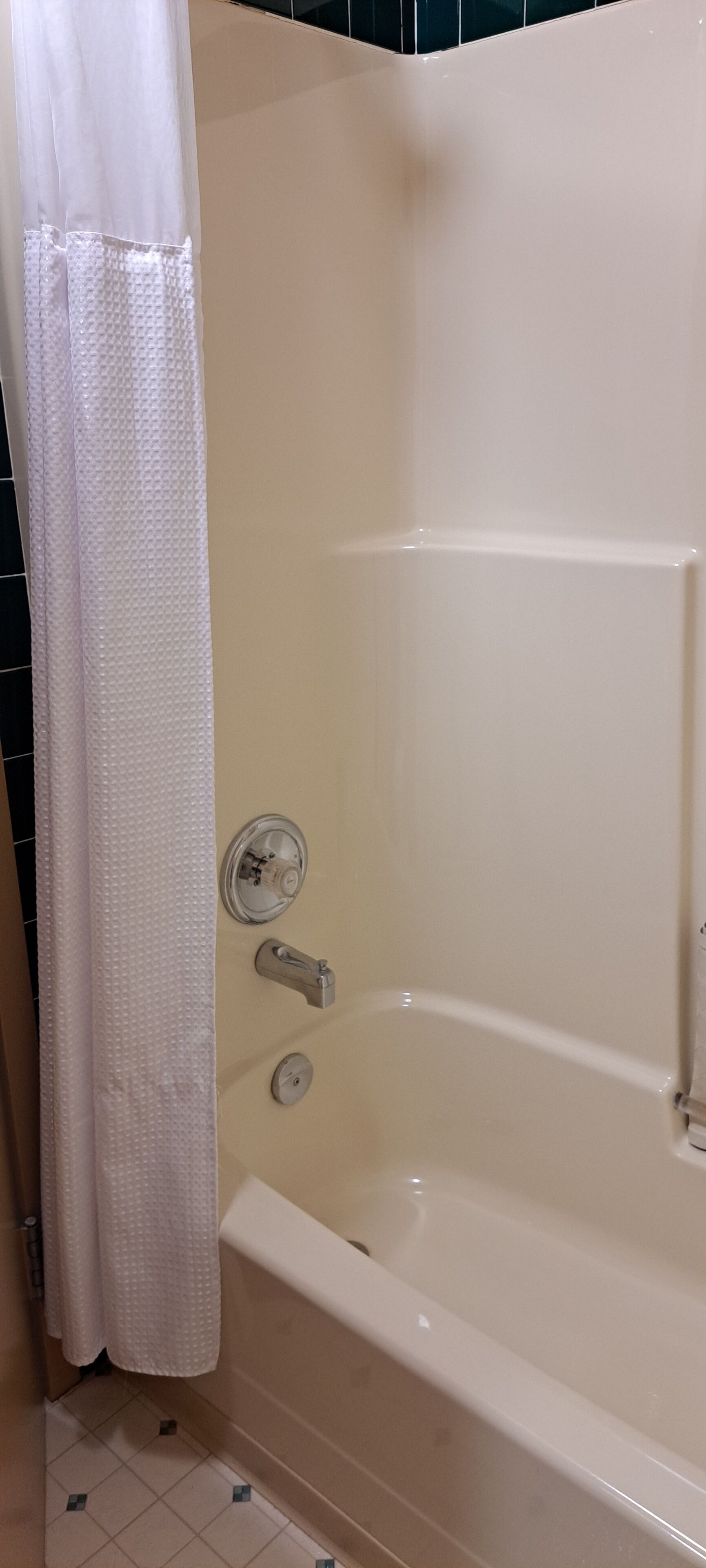 A bathtub with a shower curtain, a control knob, and a faucet.