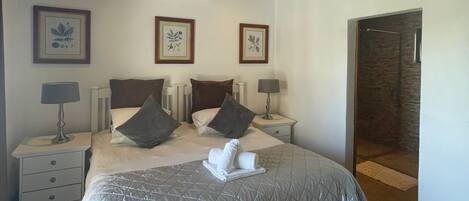 Een slaapkamer met een groot bed, twee nachtkastjes, een wandairconditioner en een deur naar een badkamer.