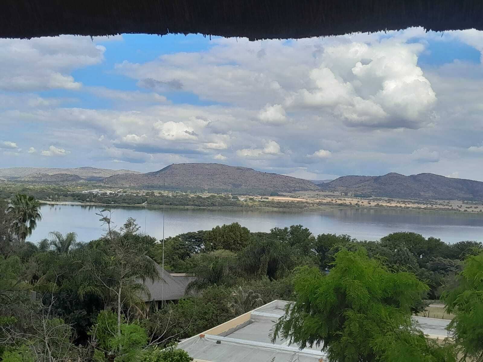 Une vue sur un lac, avec des montagnes en arrière-plan, le tout entouré de verdure.