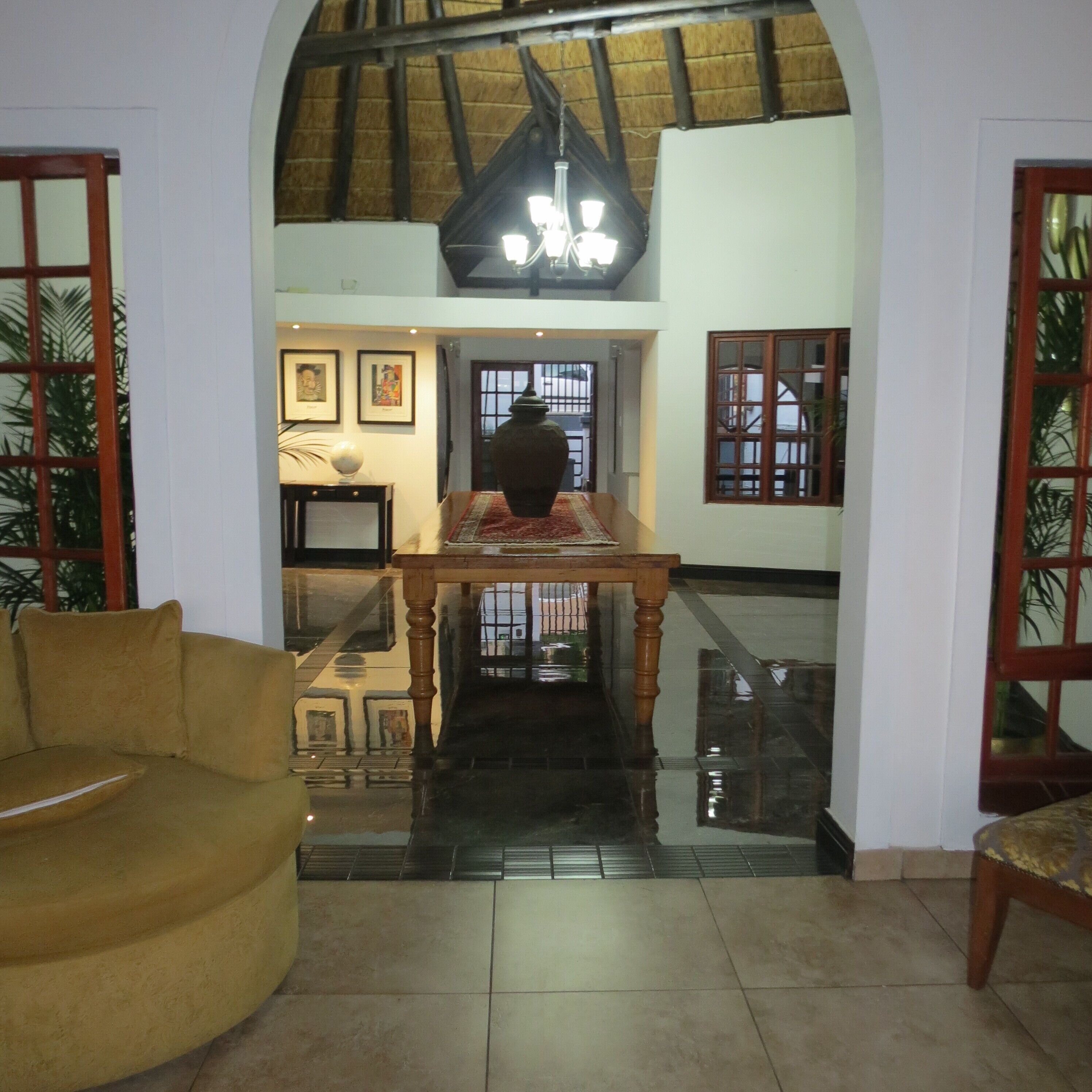 An interior with a high ceiling, a staircase, a dining table, and a sofa.