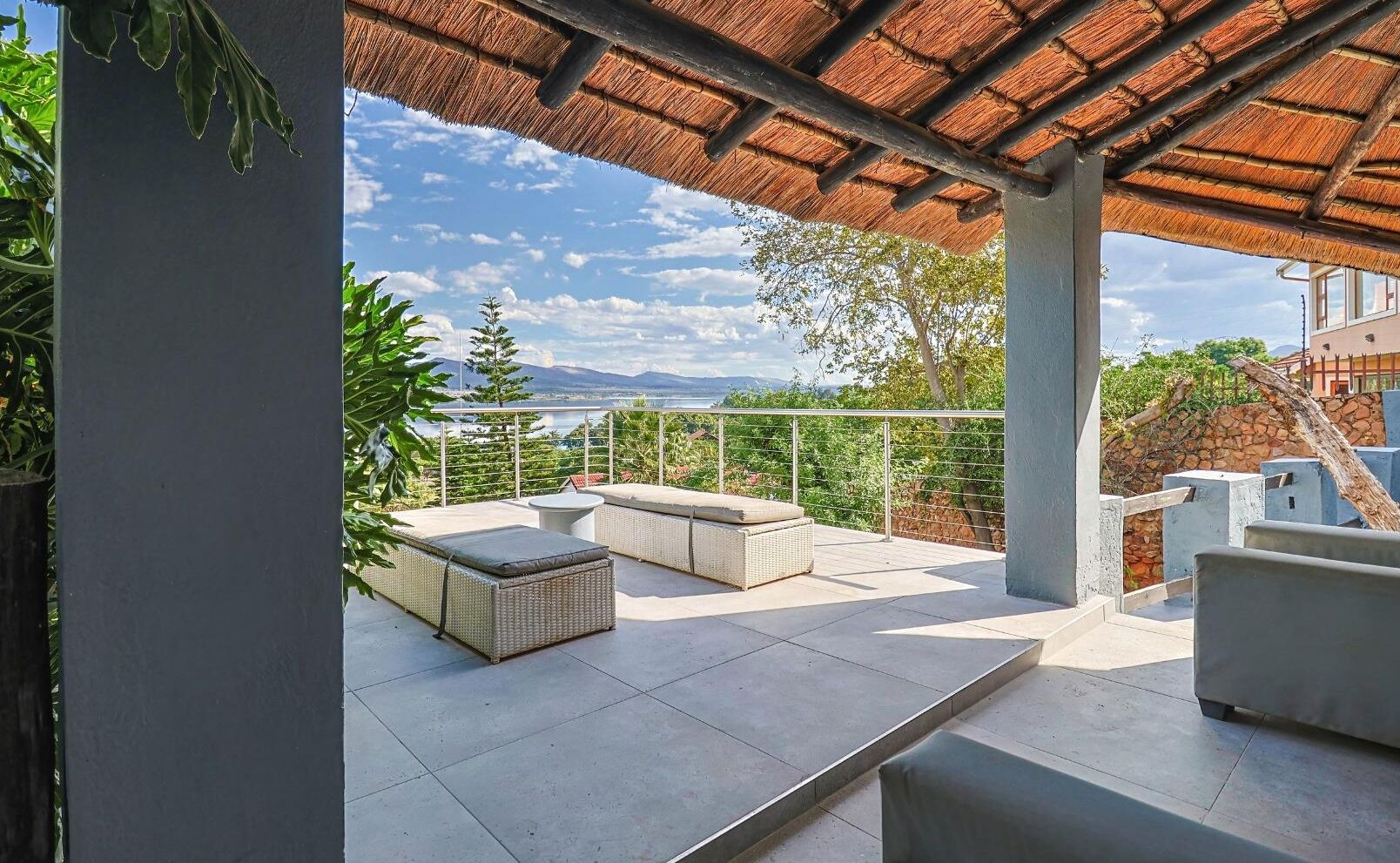 Um alpendre coberto com vista para montanhas, um sofá branco e uma mesa de jantar.