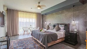 A bedroom with a bed, bedside tables, a desk, a chair, a rug, and a window with curtains. - Galagos Lodge (Hartbeespoort)