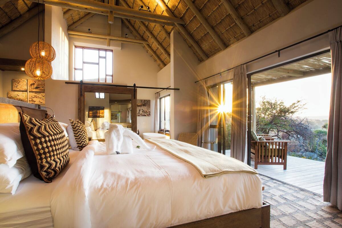 A spacious bedroom with a large bed, a wooden headboard, and a view of the outdoors through a sliding glass door.