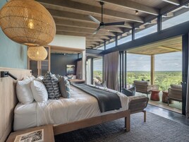 Um quarto espaçoso com uma cama grande, vista para a paisagem e um ventilador de teto.