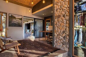 A modern interior with a stone wall, a wooden ceiling, and a view of a garden. - Klaserie Drift Misava (Bushbuckridge)