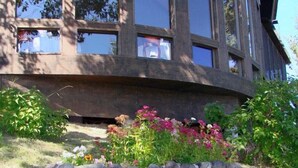 Un bâtiment avec des fondations en pierre et un jardin où poussent différentes plantes et fleurs.