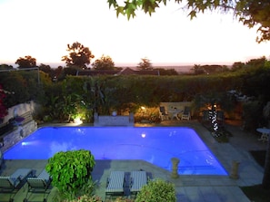 Piscina com espreguiçadeiras e vista para o pôr do sol.
