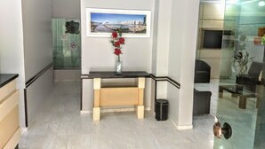 A modern interior with a desk, a framed picture on the wall, and a vase with red flowers. - Master Hotel (Balneário Camboriú)