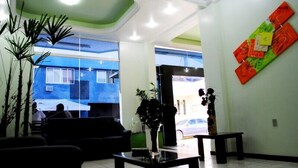 A reception area with a seating area, a reception desk, and a large window with a view of the outside. - Master Hotel (Balneário Camboriú)