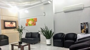 A modern waiting area with a flat-screen TV, comfortable seating, and a potted plant. - Master Hotel (Balneário Camboriú)