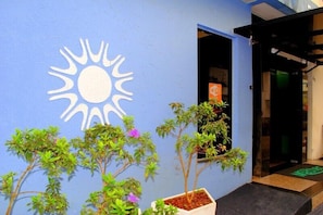 A building entrance with a blue wall, a sun symbol, and potted plants. - Master Hotel (Balneário Camboriú)
