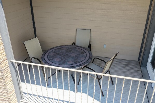 A balcony with a round table and four chairs, a white railing, and a beige wall. - Best Western Plus North Platte Inn & Suites (North Platte)