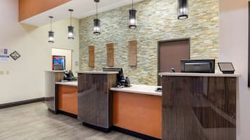 A reception area with a stone wall, wooden reception desk, and pendant lighting.