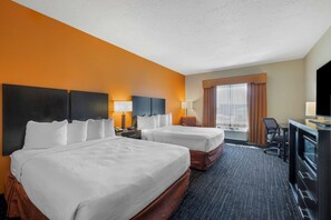 A hotel room with two beds, a desk, a TV, and a window with curtains.