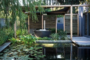 Ein friedlicher Garten mit Teich, Holzterrasse und einer Pergola.