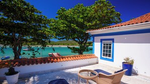 A balcony with wicker furniture, a potted plant, and a view of the sea and boats. - Hotel Solar do Arco (Cabo Frio)