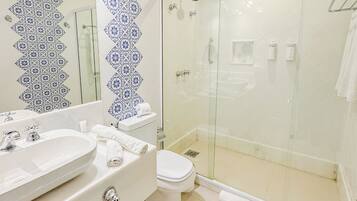 Une salle de bain avec une douche à parois de verre, un lavabo blanc et des toilettes.