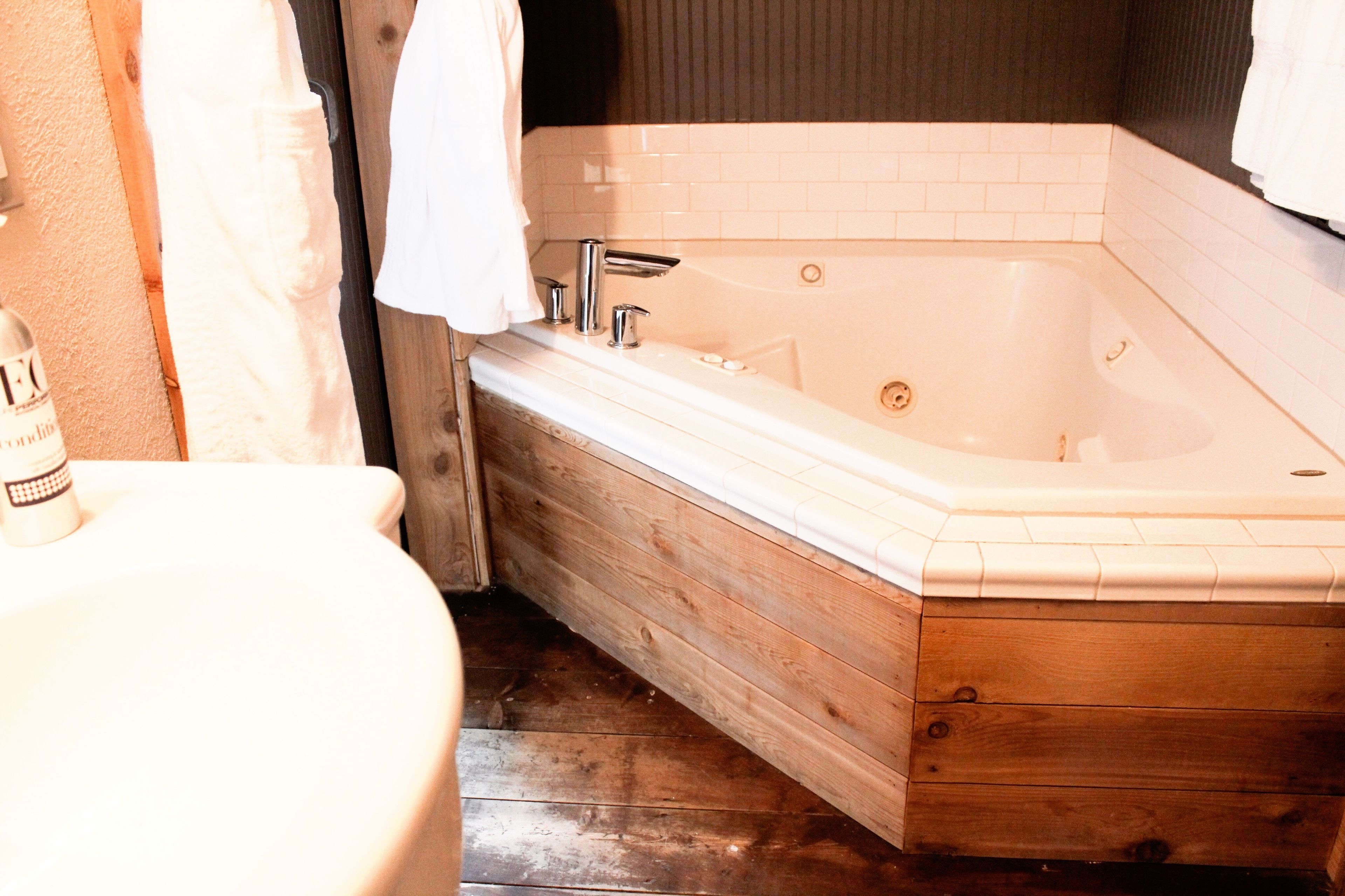 Ein Badezimmer mit einer Holzwanne, einem weißen Waschbecken und einer Toilette.