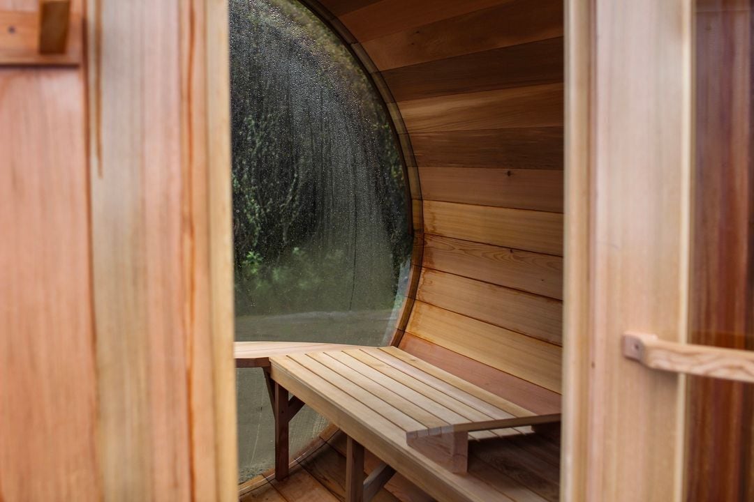A sauna with a wooden bench and a large circular window.