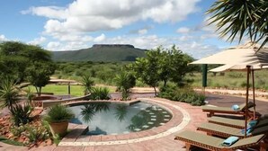 A pool area with lounge chairs and a view of a mountain. - Waterberg Guest Farm (Otjiwarongo)