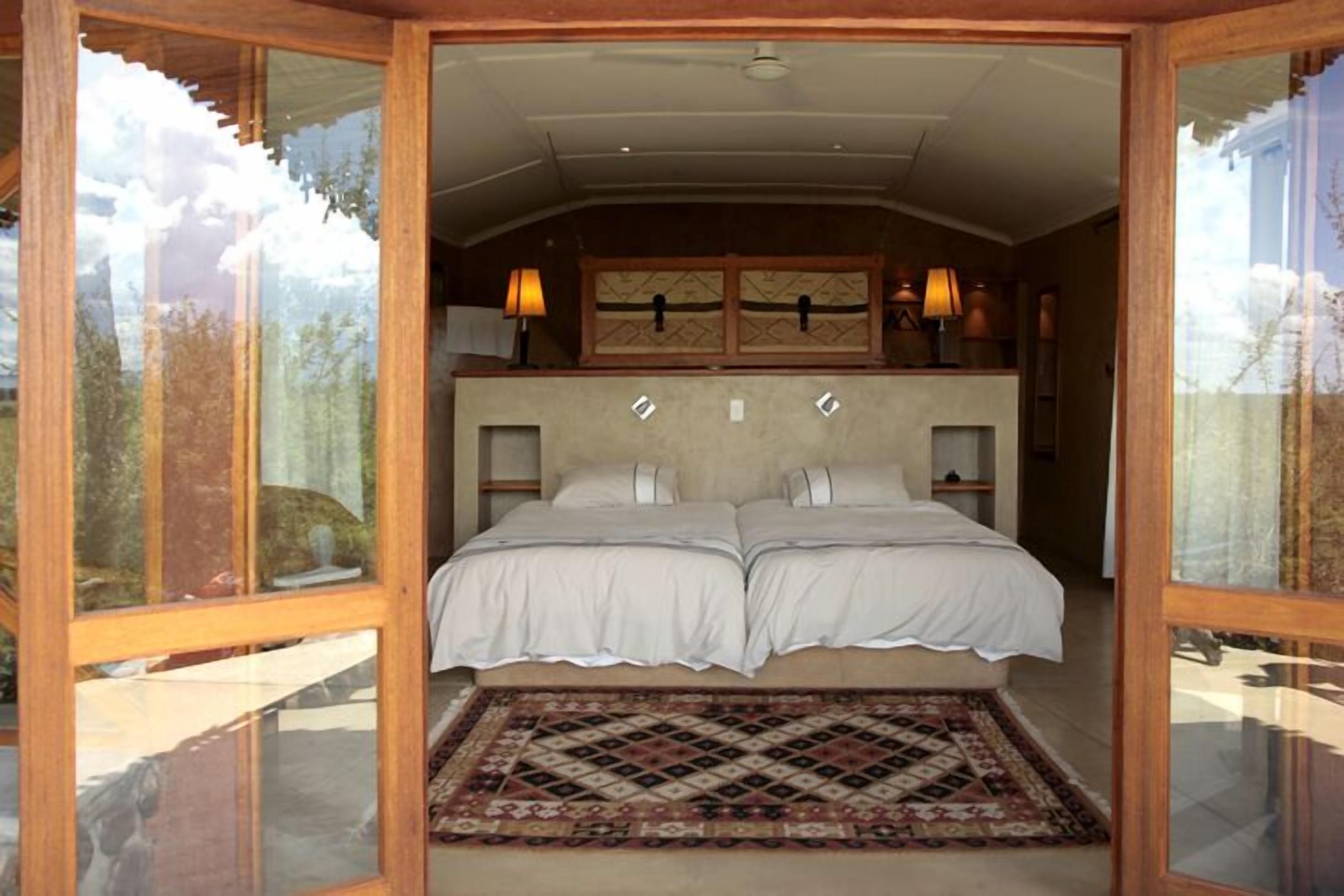 A double bed with a headboard, a patterned rug, and two bedside lamps.
