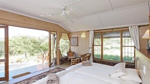 A bedroom with a large bed, a ceiling fan, and a view of greenery outside. - Waterberg Guest Farm (Otjiwarongo)