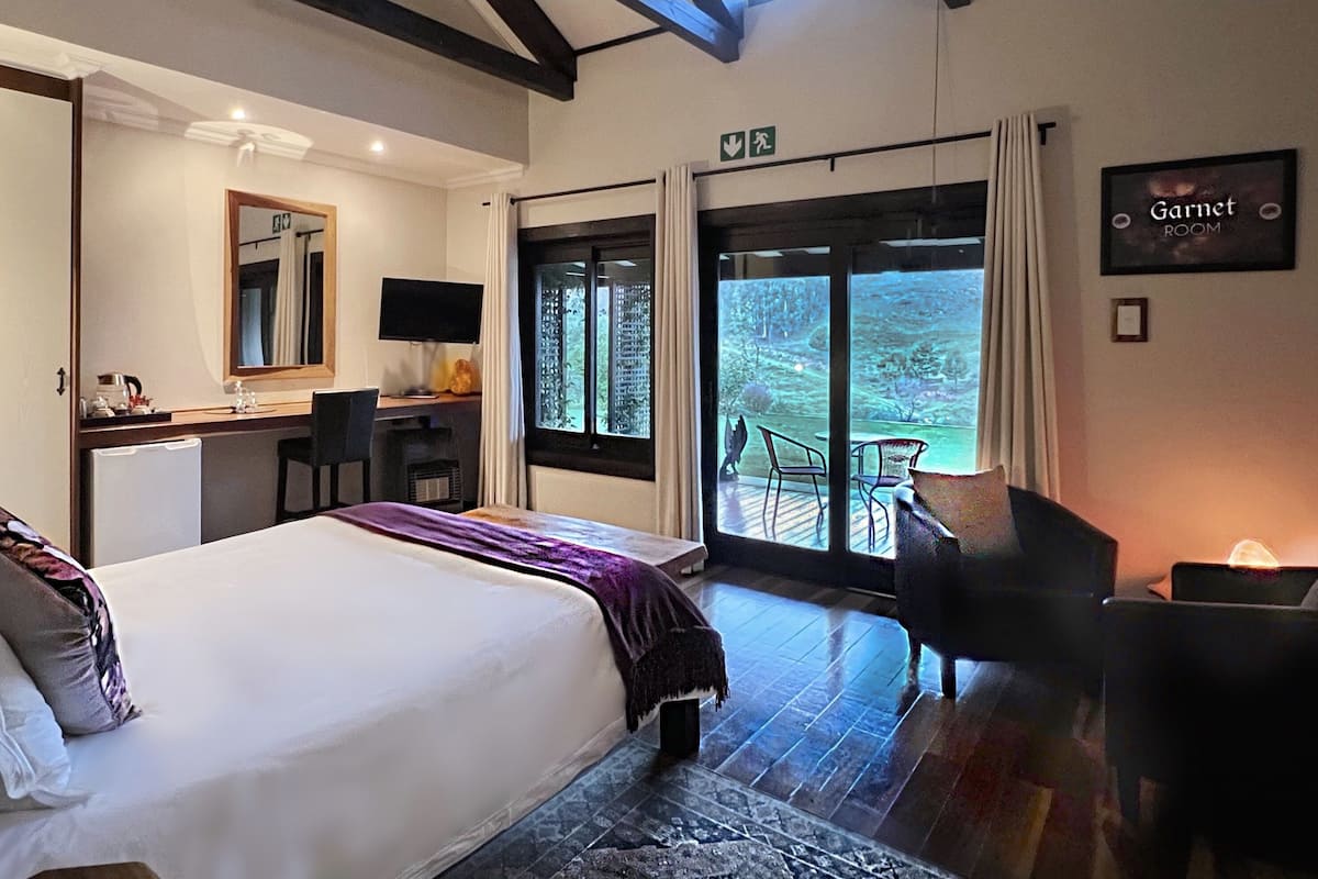 Habitación de hotel con cama, escritorio, silla y vistas al exterior.