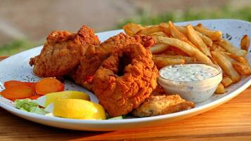 Un plato de pollo frito, papas fritas y una guarnición de ensalada de col con cuñas de limón.