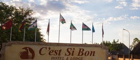 A hotel sign with multiple flags and a giraffe logo.