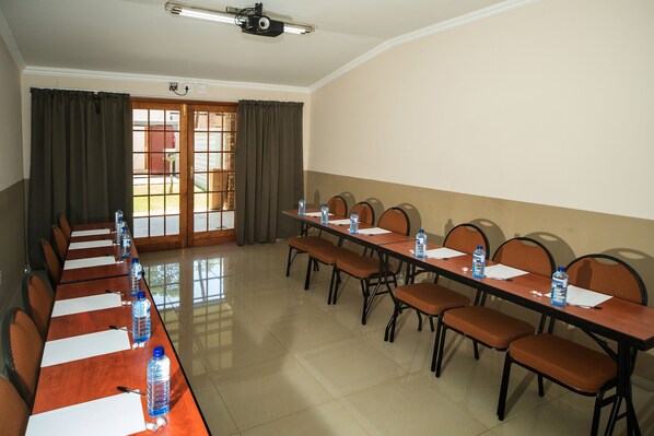 A conference room with a long table, chairs, water bottles, and a projector.