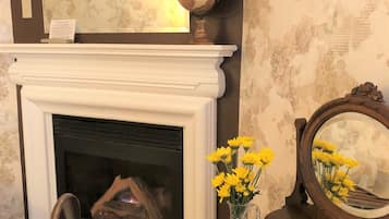 A room with a fireplace, a globe, a mirror, and a vase with flowers.