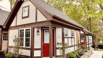 A traditional half-timbered cottage with a red door, white windows, and a sign indicating it is number 15 on Pemetic Mountain.