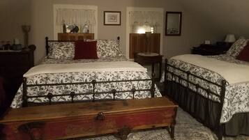 A bedroom with two beds, a wooden dresser, a nightstand, and a lamp.