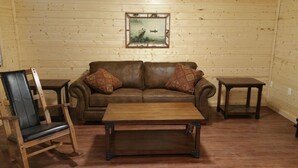A cozy room with a brown leather sofa, two matching armchairs, a wooden coffee table, and a framed picture on the wall.
