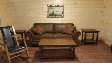 Un cuarto acogedor con un sofá de cuero marrón, dos sillones a juego, una mesa de centro de madera y un cuadro enmarcado en la pared.