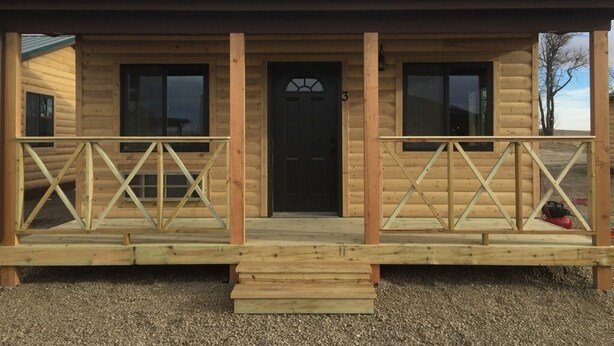 A wooden cabin with a porch, a black door, and a number '3' on the front.