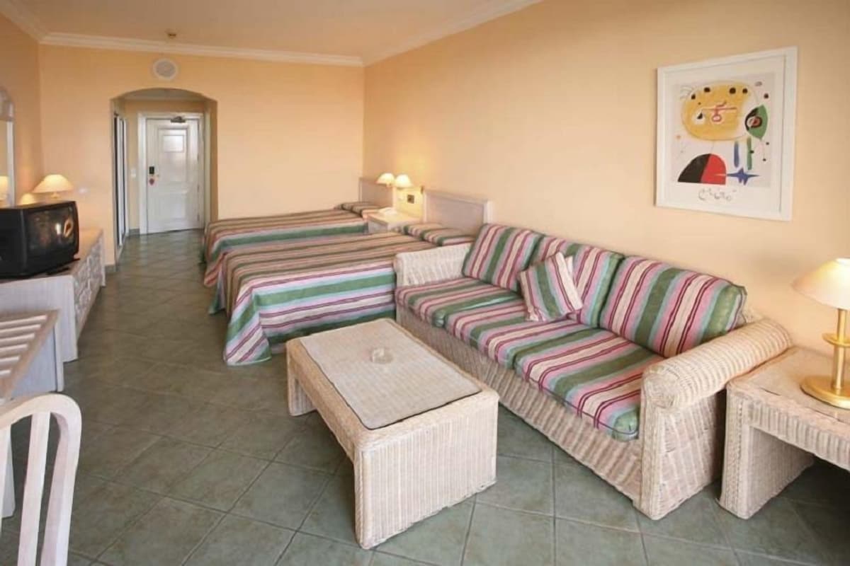 Une chambre d’hôtel avec deux lits simples, un canapé, une petite table et un téléviseur.