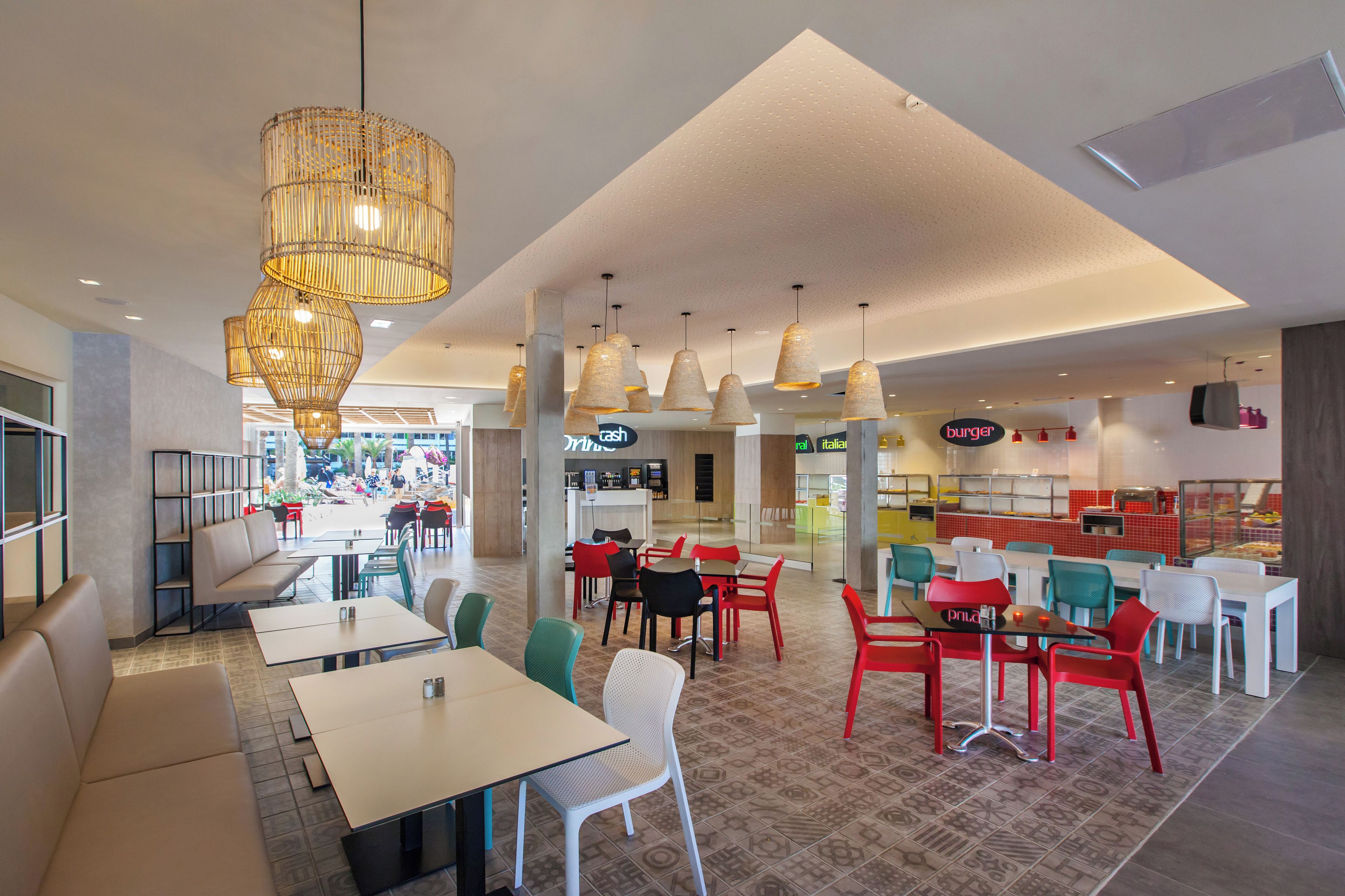 A modern restaurant interior with high ceilings, pendant lighting, and a mix of seating styles including tables and chairs.