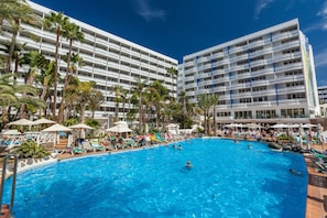A large swimming pool surrounded by palm trees and lounge chairs, with a multi-story hotel building in the background. - Abora Buenaventura by Lopesan Hotels (San Bartolomé de Tirajana)