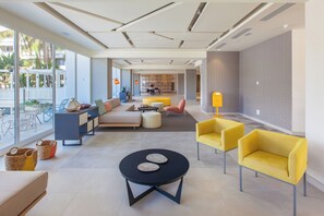 A modern interior with a sofa, yellow chairs, a round table, and a bookshelf. - Abora Buenaventura by Lopesan Hotels (San Bartolomé de Tirajana)