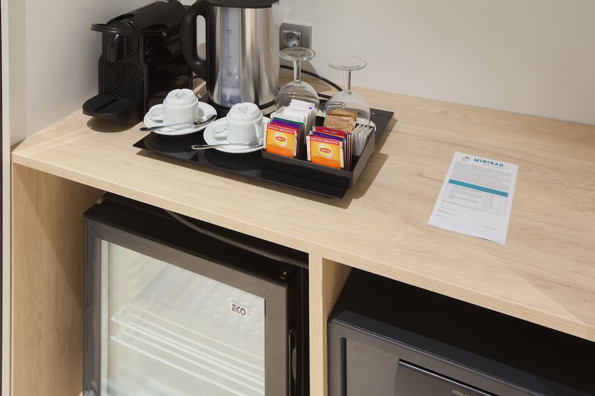 Un coin petit-déjeuner équipé d’une machine à café, d’une théière, de tasses et de divers aliments pour le petit-déjeuner.