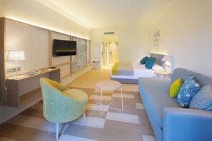 A modern hotel room with a flat-screen TV, a sofa, a chair, a bed, and a small table. - Abora Buenaventura by Lopesan Hotels (San Bartolomé de Tirajana)