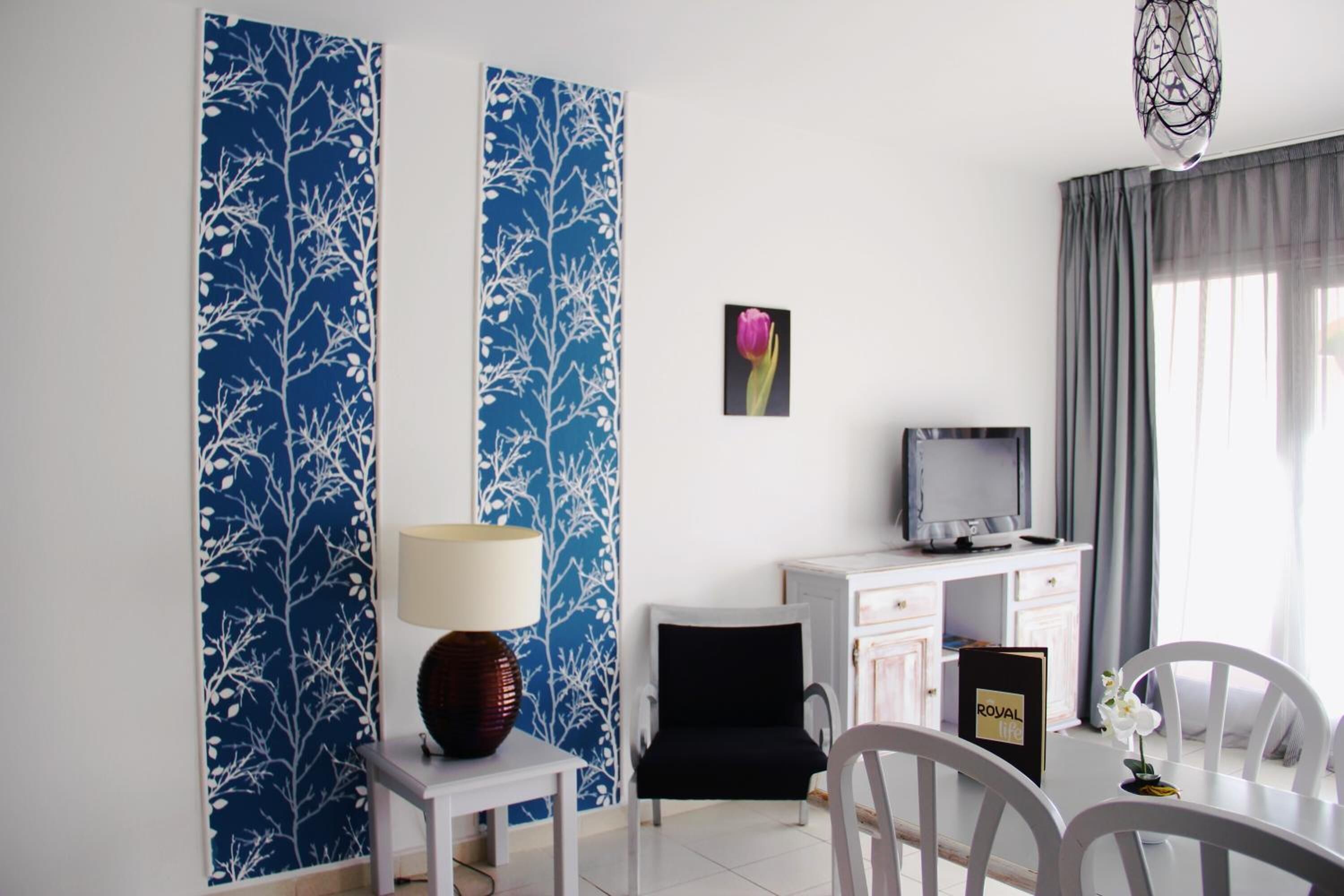 A hotel room with a dining area, a TV, and a decorative wall panel.
