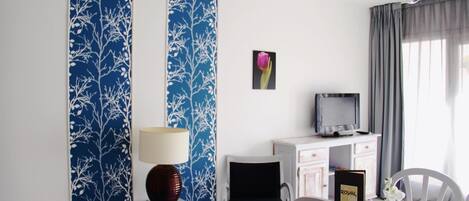 A hotel room with a dining area, a TV, and a decorative wall panel.