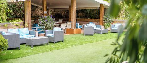 Un espacio al aire libre con mobiliario de mimbre y un porche cubierto.