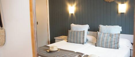 A neatly made bed with a patterned bedspread, two pillows, and a hat on the bed.