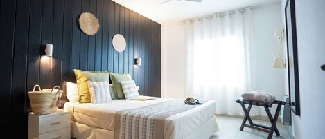 A bedroom with a bed, bedside tables, a ceiling fan, and a window with curtains.